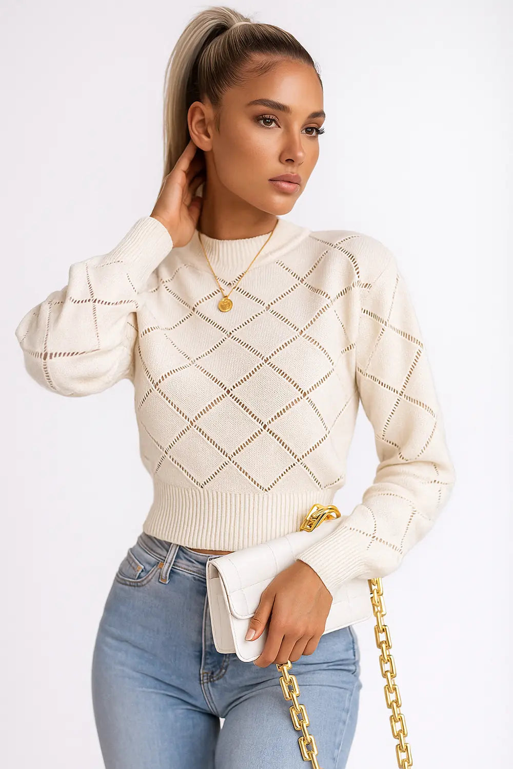 Women's cream knit sweater with diamond openwork pattern, styled with gold necklace and white chain bag